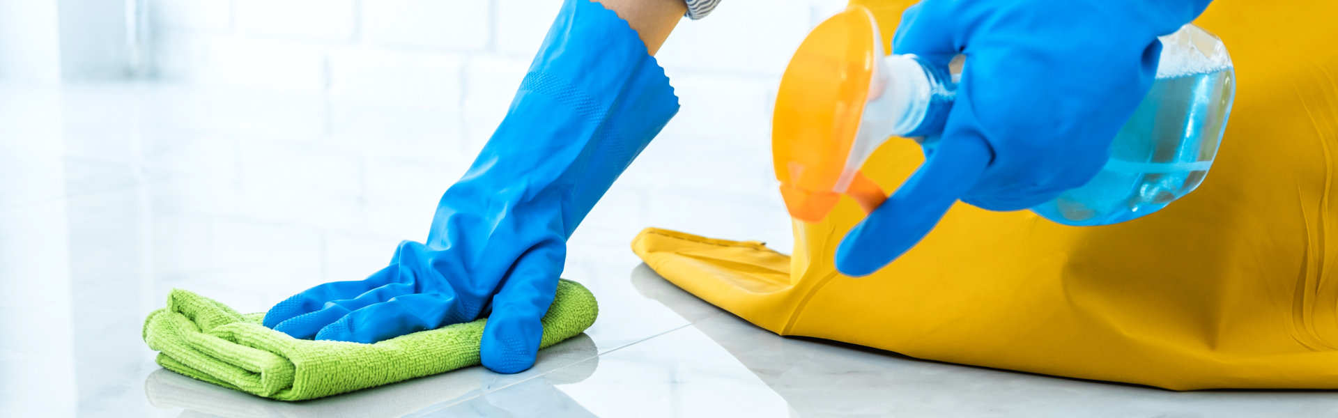 Wife housekeeping and cleaning concept, Happy young woman in blue rubber gloves wiping dust using a spray and a duster while cleaning on floor at home.